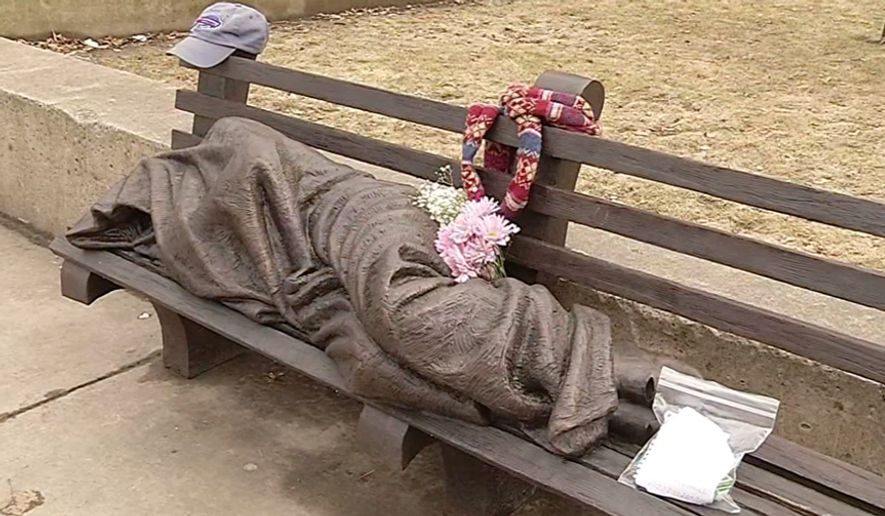 An April 3, 2015 image from video shows a work by Canadian sculptor Timothy Schmalz, a blanket-shrouded Jesus identifiable only by the crucifixion wounds on his feet, outside St. Paul's Episcopal Cathedral in Buffalo, NY. The unveiling of the statue on March 31 has prompted people to leave money, food and other items at the bronze sculpture. The offerings are apparently meant for Buffalo's homeless. (AP Photo/courtesy of WIVB-TV) BUFFALO OUT