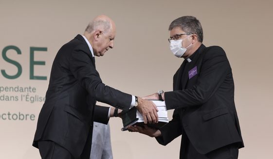 Commission President Jean-Marc Sauve, left, hands copies of the report to Catholic Bishop Eric de Moulins-Beaufort, president of the Bishops&#39; Conference of France (CEF), during the publishing of a report by an independent commission into sexual abuse by church officials (Ciase), Tuesday, Oct. 5, 2021, in Paris. A major French report released Tuesday found that an estimated 330,000 children were victims of sex abuse within France&#39;s Catholic Church over the past 70 years, in France&#39;s first major reckoning with the devastating phenomenon. (Thomas Coex, Pool via AP)