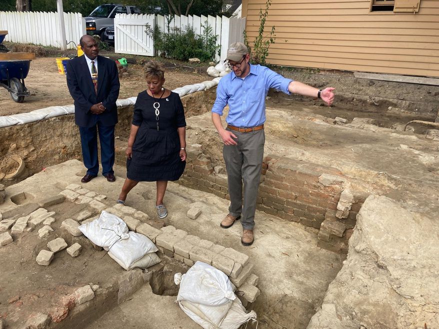 Reginald F. Davis, from left, pastor of First Baptist Church in Williamsburg, Connie Matthews Harshaw, a member of First Baptist, and Jack Gary, Colonial Williamsburg&#39;s director of archaeology, stand at the brick-and-mortar foundation of one the oldest Black churches in the U.S. on Wednesday, Oct. 6, 2021, in Williamsburg, Va. Colonial Williamsburg announced Thursday Oct. 7, that the foundation had been unearthed by archeologists. (AP Photo/Ben Finley)