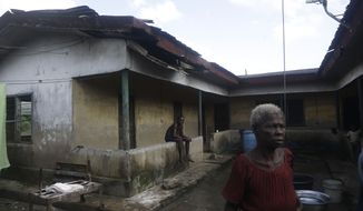 Christiana Eluozu stands outside her house with a damaged roof that she claims was damaged as a result of gas flare belonging to the Agip Oil company in Idu, Niger Delta area of Nigeria, Friday, Oct. 8, 2021. (AP Photo/Sunday Alamba)