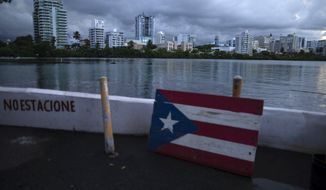 A wooden Puerto Rican flag is displayed on the dock of the Condado lagoon, where multiple selective blackouts have been recorded in the past days, in San Juan, Puerto Rico, Thursday, Sept. 30, 2021. Federal agents arrested the mayor of one of the wealthiest cities in Puerto Rico on corruption charges Thursday, the second such case announced this month. (AP Photo/Carlos Giusti)