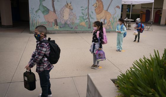 In this April 13, 2021, photo, socially distanced kindergarten students wait for their parents to pick them up on the first day of in-person learning at Maurice Sendak Elementary School in Los Angeles. The number of Americans getting COVID-19 vaccine shots is nearing an average of 1 million per day. Demand is expected to spike in a few weeks when elementary school-age children can begin getting vaccinated. (AP Photo/Jae C. Hong) **FILE**
