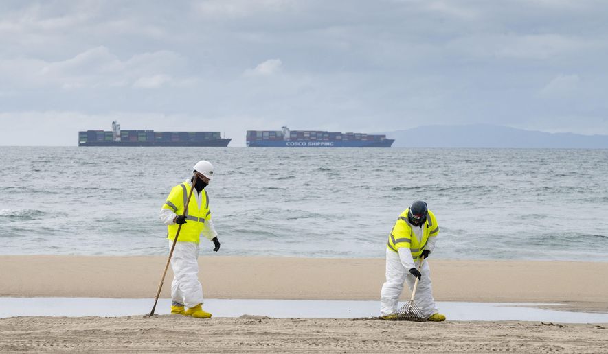 Workers with Patriot Environmental Services clean the sand south of the pier in Huntington Beach, Calif. on Friday, Oct. 8, 2021. Investigators searching for the cause of an undersea oil pipeline break off the Southern California coast have pointed to the possibility that a ship anchor dragged the line across the seabed and cracked it, but two videos released so far provide only tantalizing clues about what might have happened below the ocean surface.  (Paul Bersebach/The Orange County Register via AP)