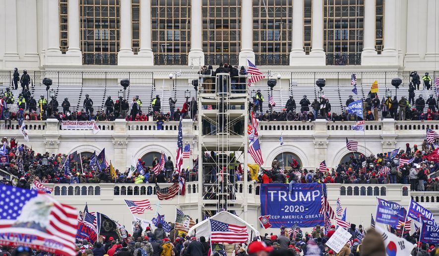 In this Jan. 6, 2021, file photo insurrectionists loyal to President Donald Trump breach the Capitol in Washington. Like many Donald Trump supporters who stormed the U.S. Capitol on Jan. 6, Dona Sue Bissey has promoted the QAnon conspiracy theory on social media. But the judge sentencing her Tuesday to 14 days in jail said it was for her actions, not her beliefs. (AP Photo/John Minchillo) **FILE**