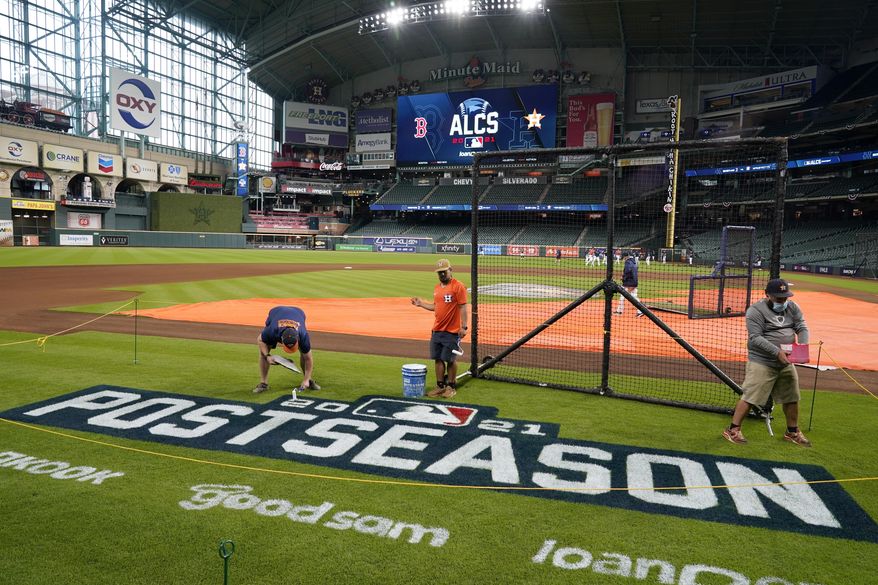 Grounds crew personnel apply the final touches to a postseason field logo at Minute Maid Park before baseball practice in Houston, Thursday, Oct. 14, 2021. The Houston Astros host the Boston Red Sox in Game 1 of the American League Championship Series on Friday. (AP Photo/Tony Gutierrez) **FILE**