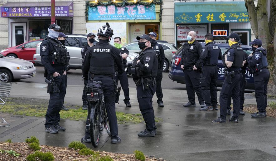 FILE - Seattle Police officers confer after taking part in a public roll call at Hing Hay Park in Seattle&#39;s Chinatown-International District Thursday, March 18, 2021. Seattle&#39;s police department is having detectives and non-patrol staff respond to emergency calls because of a shortage of officers union leaders fear will be made worse by COVID-19 vaccine mandates. (AP Photo/Ted S. Warren, File)