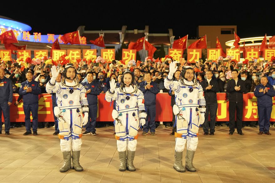 In this photo released by Xinhua News Agency, Chinese astronauts from left, Ye Guangfu, Wang Yaping and Zhai Zhigang wave before leaving for their Shenzhou-13 crewed space mission at the Jiuquan Satellite Launch Center in northwest China, Oct. 15, 2021. Shortly ahead of sending a new three-person crew to its space station, China on Friday renewed its commitment to international cooperation in the peaceful use of space. (Li Gang/Xinhua via AP)