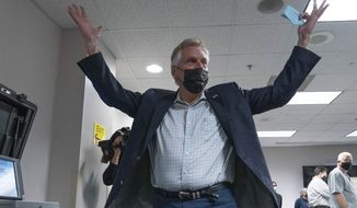 Virginia Democratic gubernatorial candidate and former Gov. Terry McAuliffe raises his arms after he cast his vote at County Government Center in Fairfax, Va. Wednesday, Oct. 13, 2021. (AP Photo/Jose Luis Magana) ** FILE **