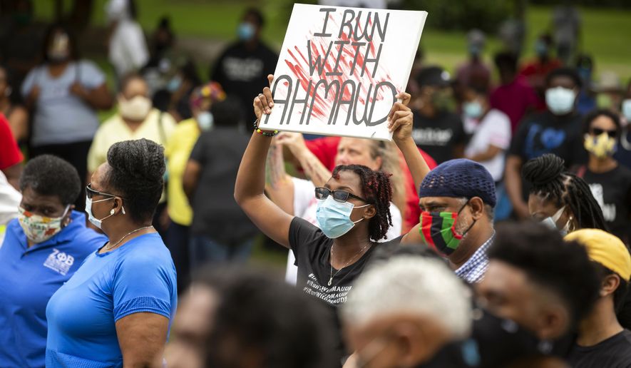 FILE - In this May 16, 2020, file photo, a woman holds a sign during a rally to protest the shooting of Ahmaud Arbery, in Brunswick, Ga. Arbery was shot and killed while running in a neighborhood outside the port city. Jury selection in the case is scheduled to begin Monday, Oct. 18. (AP Photo/Stephen B. Morton, File)