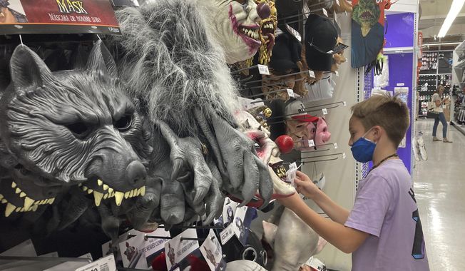 A young customer looks at a Halloween mask at a Party City store, Wednesday, Oct. 6, 2021, in Miami.  Americans continued to spend at a solid clip in September despite rising prices and snarled global supply chains that are limiting the flow of goods. Retail sales rose a seasonally adjusted 0.7%  in September  from the month before, the U.S. Commerce Department said Friday, Oct. 15.  (AP Photo/Marta Lavandier)