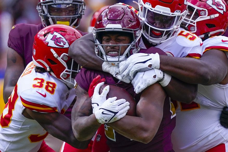 Washington Football Team running back Antonio Gibson (24) clutches the football as he is tackled by Kansas City Chiefs outside linebacker Nick Bolton (54) during the first half of an NFL football game, Sunday, Oct. 17, 2021, in Landover, Md. (AP Photo/Alex Brandon)