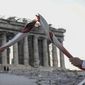 Greek torch bearer Ioannis Melissanidis, left, Olympic gold medalist in Gymnastics, passes the flame to Christos Volikakis, world Champion in Cycling, in front of the ancient Parthenon temple atop of the Acropolis Hill in Athens, Tuesday, Oct. 19, 2021. The flame will be transported by torch relay to Beijing, China, which will host the Feb. 4-20, 2022, Winter Olympics.(AP Photo/Petros Giannakouris)