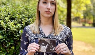 Kyndal Nipper, of Midland, Ga., who suffered a stillbirth after becoming ill with COVID-19 in her third trimester, holds an ultrasound image of the son she lost while standing outside her home on Friday, Oct. 15, 2021. Nipper, who was unvaccinated, is encouraging women to get vaccinated. (AP Photo/Kim Chandler)