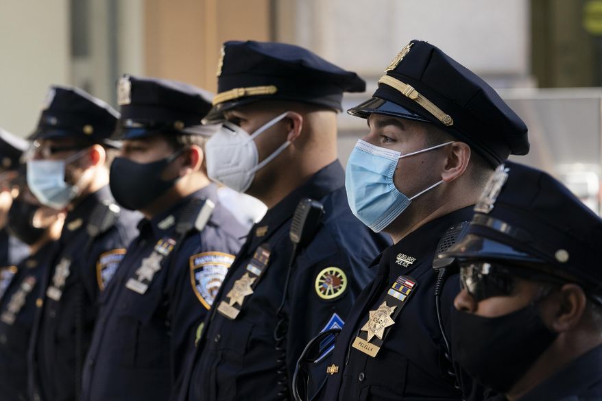 In this Oct. 5, 2020, photo, New York Police Department officers in masks stand during a service at St. Patrick&#39;s Cathedral in New York to honor 46 colleagues who have died due to COVID-19 related illness. New York City will require police officers, firefighters and other municipal workers to be vaccinated against COVID-19 or be placed on unpaid leave, Mayor Bill de Blasio said Wednesday, Oct. 20, 2021, giving an ultimatum to public employees who’ve refused and ensuring a fight with some of the unions representing them. (AP Photo/Mark Lennihan) **FILE**