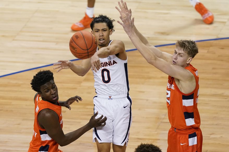 In this March 11, 2021, file photo, Virginia guard Kihei Clark (0) passes the ball from between Syracuse forwards Kadary Richmond, left, and Marek Dolezaj during the second half of an NCAA college basketball game in the quarterfinalsof the Atlantic Coast Conference tournament in Greensboro, N.C. Clark is back for his senior season, and he&#39;s already spent three with a leadership role by virtue of his position. “I’m just trying to do a good job of leading those guys and then especially the new guys, the two transfers and then the freshmen coming in,” Clark said. (AP Photo/Gerry Broome, File) *FILE**
