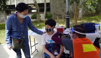 In this May 14, 2021, file photo, Colin Sweeney, 12, gets a shot of the Pfizer COVID-19 vaccine as his mother Nicole pats his shoulder at the First Baptist Church of Pasadena in Pasadena, Calif. Public health departments across California are gearing up to administer coronavirus vaccines to children ages 5 to 11 in the coming weeks and officials say they are planning &quot;family-friendly&quot; events, including at schools, to convince parents to get their kids the shots. The White House on Wednesday, Oct. 20, detailed plans for the expected authorization of the Pfizer shot for elementary school youngsters in a matter of weeks. (AP Photo/Marcio Jose Sanchez, File)