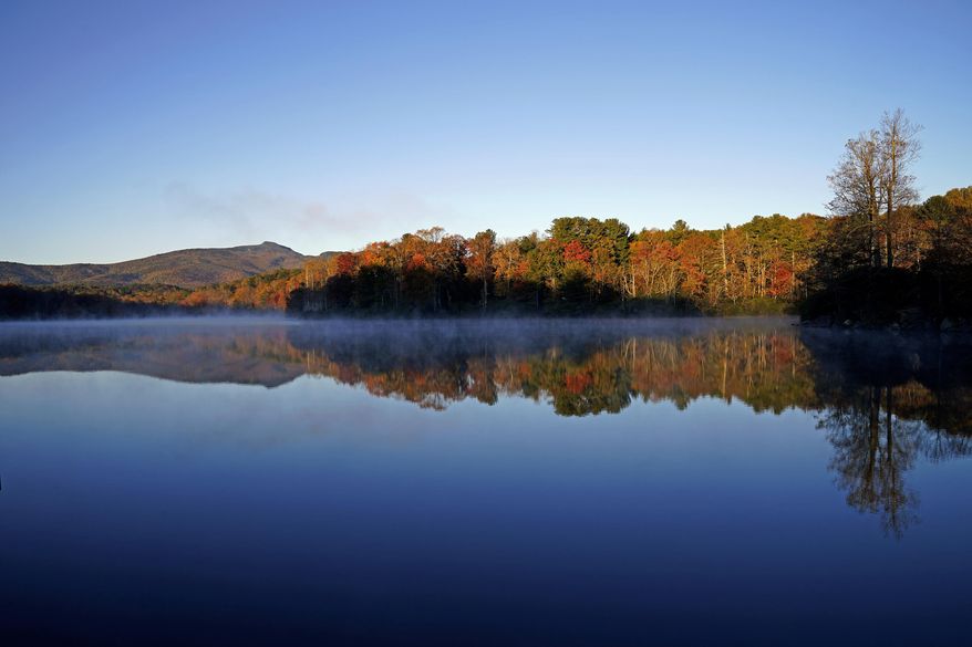 Price Lake reflects fall foliage as the sun rises along the Blue Ridge Parkway near Blowing Rock, N.C., Tuesday, Oct. 19, 2021. (AP Photo/Gerry Broome)