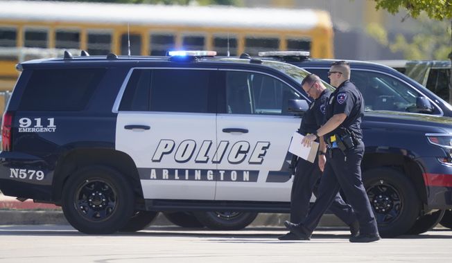 In this Wednesday, Oct. 6, 2021, file photo, law enforcement officers walk in the parking lot of Timberview High School after a shooting inside the school located in south Arlington, Texas. A 15-year-old injured in the Timberview High School shooting earlier this month was released from the hospital over the weekend, Arlington police said. (AP Photo/LM Otero, File)