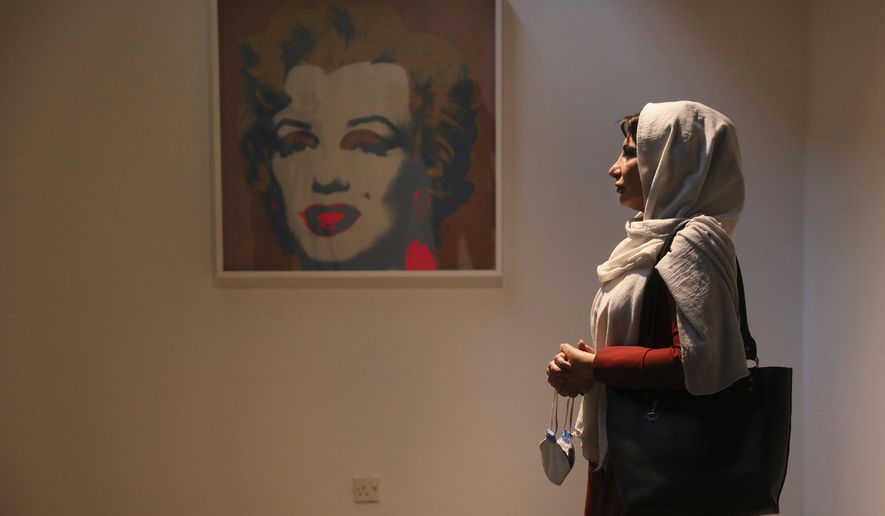 Fatemeh Rezaei, a retired teacher, stands next to Marilyn Monroe portrait by American artist Andy Warhol at Tehran Museum of Contemporary Art in Tehran, Iran on Oct. 19, 2021. Iranians are flocking to Tehran&#39;s contemporary art museum to marvel at American pop artist Andy Warhol’s iconic work. (AP Photo/Vahid Salemi)