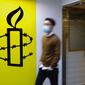 A man walks past the logo of the Amnesty International at its office in Hong Kong Monday, Oct. 25, 2021. Amnesty International said Monday it would close its two offices in Hong Kong this year, becoming the latest non-governmental organization to cease its operations amid a crackdown on political dissent in the city. (AP Photo/Vincent Yu)