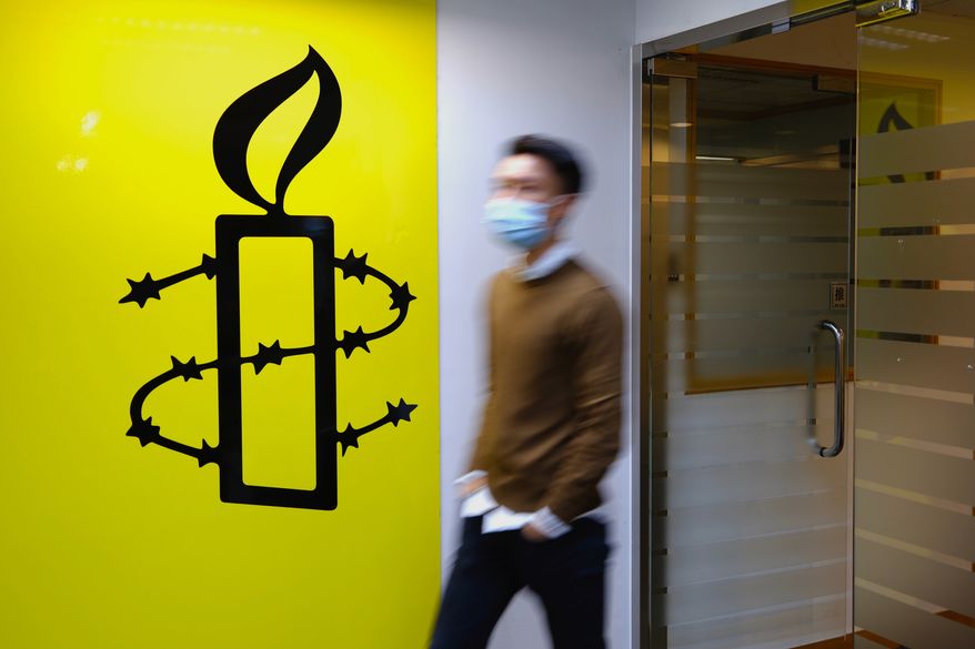 A man walks past the logo of the Amnesty International at its office in Hong Kong Monday, Oct. 25, 2021. Amnesty International said Monday it would close its two offices in Hong Kong this year, becoming the latest non-governmental organization to cease its operations amid a crackdown on political dissent in the city. (AP Photo/Vincent Yu)