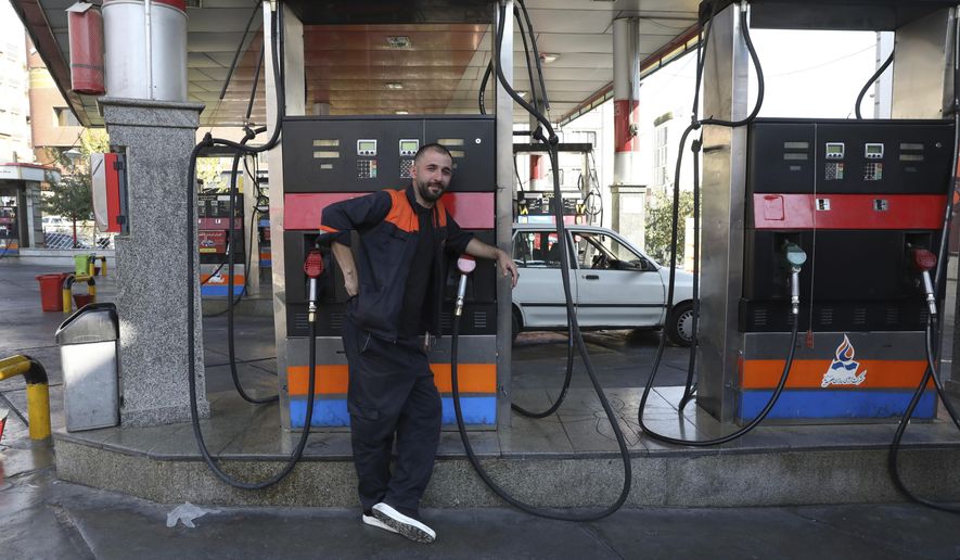 A worker leans against a gasoline pump that has been turned off, at a gas station in Tehran, Iran, Tuesday, Oct. 26, 2021. Gas stations across Iran on Tuesday suffered through a widespread outage of a system that allows consumers to buy fuel with a government-issued card, stopping sales. One semiofficial news agency referred to the incident as a cyberattack. (AP Photo/Vahid Salemi)