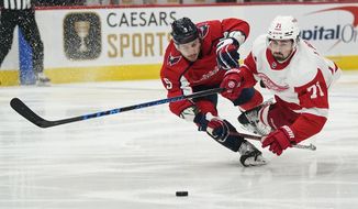 Washington Capitals defenseman Dmitry Orlov (9) and Detroit Red Wings center Dylan Larkin (71) dive for the puck in the first period of an NHL hockey game, Wednesday, Oct. 27, 2021, in Washington. (AP Photo/Alex Brandon)