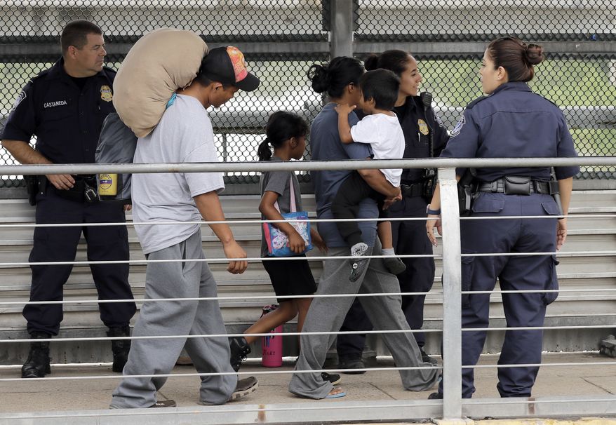 In this Thursday, June 21, 2018, file photo, Ever Castillo (left) and his family, immigrants from Honduras, are escorted back across the border by U.S. Customs and Border Patrol agents in Hildalgo, Texas. The U.S. Justice Department is in talks to pay hundreds of thousands of dollars to each child and parent who was separated under a Trump-era practice of splitting families at the border. (AP Photo/David J. Phillip) ** FILE **
