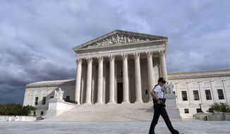 A police officer walks by the U.S. Supreme Court Thursday, Oct. 28, 2021, in Washington. (AP Photo/Jose Luis Magana) **FILE**