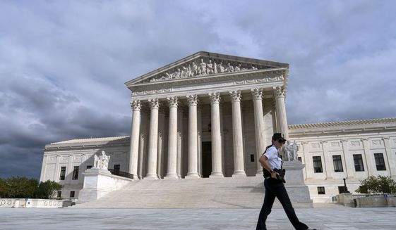 A police officer walks by the U.S. Supreme Court Thursday, Oct. 28, 2021, in Washington. (AP Photo/Jose Luis Magana) **FILE**