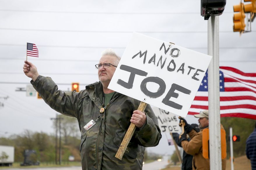Patrick Mitchell, of Owasso, holds up an American flag and a sign outside of American Airlines Maintenance Facility while protesting COVID-19 vaccine mandates on Thursday, Oct. 28, 2021 in Tulsa, Okla. (Ian Maule /Tulsa World via AP)