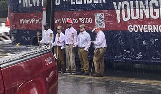 In this image provided by NBC29, five people holding tiki torches stand in the rain by the campaign bus for GOP gubernatorial candidate Glenn Youngkin, outside the Guadalajara Mexican Restaurant on Market Street in Charlottesville, Va., Friday, Oct. 29, 2021. The anti-Donald Trump group The Lincoln Project is taking credit for the group of five people who showed up at a Charlottesville campaign stop by Youngkin. The appearance recalled the torch-bearing White supremacists who descended on the city during two days of violence in 2017. ​(Elizabeth Holmes/NBC29 via AP)