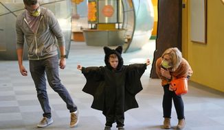 Grayson Martin, 3, poses in his costume as his parents Rachelle and Patrick Martin, look on, during a visit to Discovery Gateway Children&#39;s Museum on Thursday, Oct. 28, 2021, in Salt Lake City. Coronavirus cases in the U.S. are on the decline, and trick-or-treaters can feel safer collecting candy. (AP Photo/Rick Bowmer)