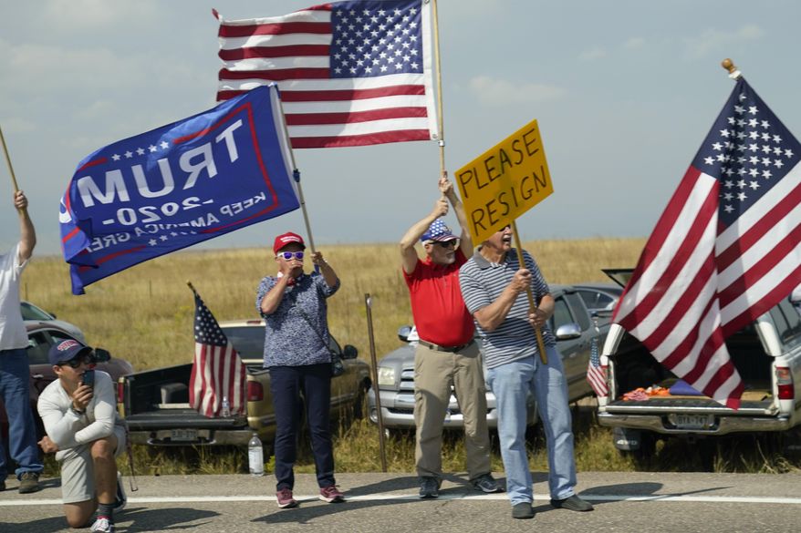 FILE - Protesters hold signs on the side of the road as seen through the window of a motorcade vehicle traveling with President Joe Biden to the Flatirons Campus of the National Renewable Energy Laboratory, on Sept. 14, 2021, in Arvanda, Colo. (AP Photo/Evan Vucci)