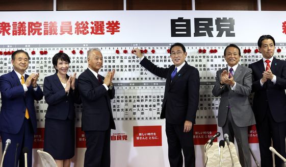 Japan&#39;s Prime Minister and ruling Liberal Democratic Party leader Fumio Kishida, third from right, poses with key party members as he puts rosettes by successful general election candidates&#39; names on a board at the party headquarters in Tokyo, Sunday, Oct. 31, 2021.  Japanese Prime Minister Fumio Kishida’s governing coalition is expected to keep a majority in a parliamentary election Sunday but will lose some seats in a setback for his weeks-old government grappling with a coronavirus-battered economy and regional security challenges, according to exit polls. (Behrouz Mehri, Pool via AP)