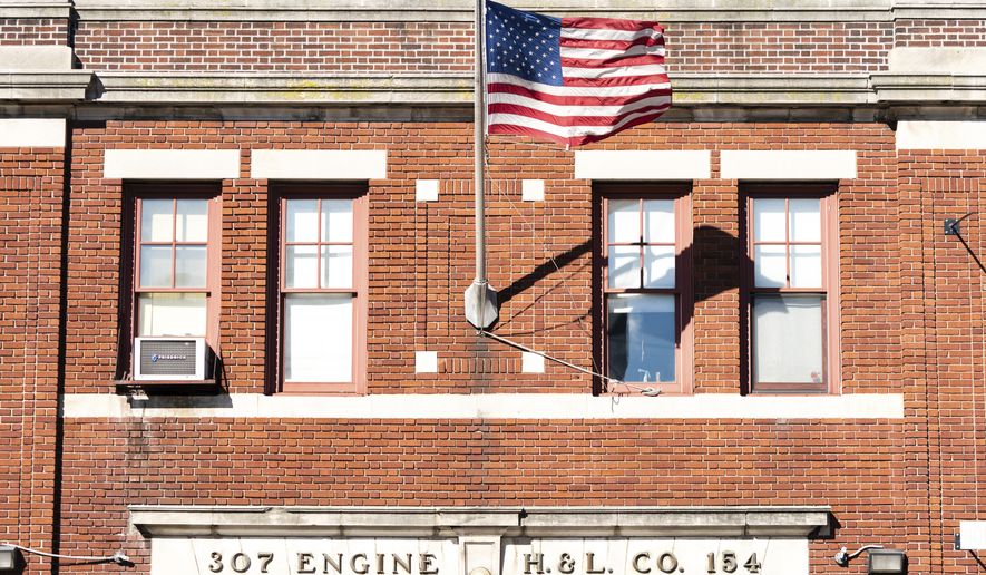 A U.S. flag flies outside FDNY Firehouse, Engine 307, Ladder 154 on Monday, Nov. 1, 2021, in New York. About 9,000 New York City municipal workers were put on unpaid leave for refusing to comply with a COVID-19 vaccine mandate that took effect Monday and thousands of city firefighters have called out sick in an apparent protest over the requirement, Mayor Bill de Blasio said. (AP Photo/Jeenah Moon)