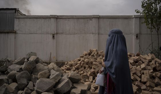 A woman passes a pile of bricks that will be used for the construction of a mosque in the Mirbacha Kot hospital, Afghanistan on Tuesday, Oct. 26, 2021. The construction of the mosque is the new manager&#39;s top priority as health care workers continue to work without salaries, without medicine and with frequent power cuts in Afghanistan&#39;s crumbling economy. (AP Photo/Bram Janssen)
