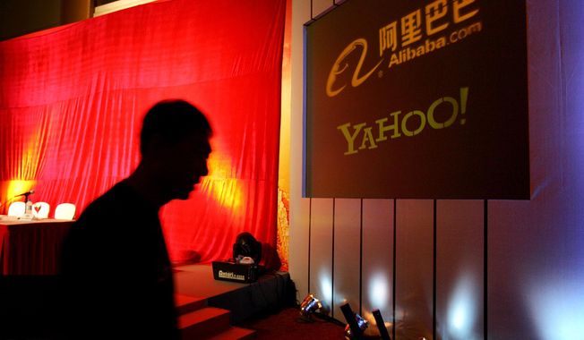 A man walks past a screen displaying the Yahoo and Alibaba.com logos before a joint news conference by the companies at the China World Hotel in Beijing, Aug. 11, 2005. Yahoo Inc. said on Tuesday, Nov. 2, 2021, that it plans to pull out of China, citing an &amp;quot;increasingly challenging business and legal environment.&amp;quot; (AP Photo/Elizabeth Dalziel, File)