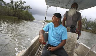 Donald Dardar, left, and Russell Dardar look toward the eroding shoreline of Bayou Pointe-au-Chien in southern Louisiana on Wednesday, Sept. 29, 2021. The brothers have lived along the bayou all their lives as shrimpers and fishermen. They now also work to preserve the coastal land from further erosion by refilling canals and developing living shorelines. (AP Photo/Jessie Wardarski)