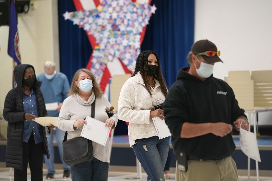 Voters hold their ballots as they wait in line to register their votes at a school in Midlothian, Va., Tuesday, Nov. 2, 2021. Voters are deciding between Democrat Terry McAuliffe and Republican Glenn Youngkin for Governor. (AP Photo/Steve Helber)