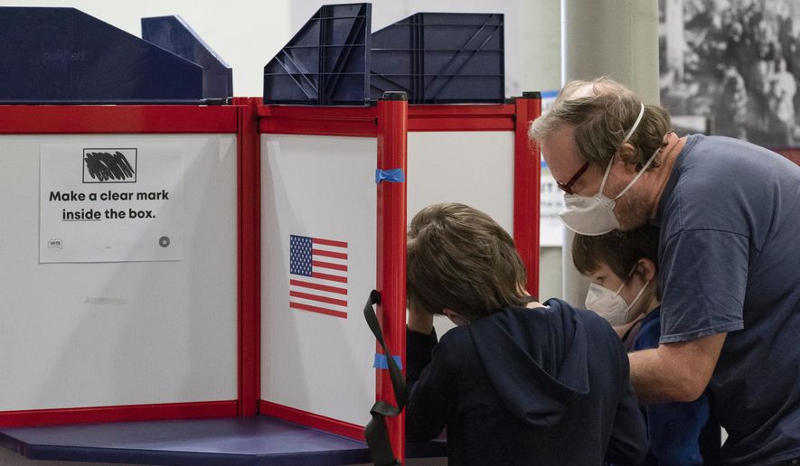 Sean Luke, right, and his sons Giacomo Luke, left, and Matteo Luke, casts his ballot on Election Day at City Hall, Tuesday, Nov. 2, 2021 in Alexandria, Va. Voters are deciding between Democrat Terry McAuliffe and Republican Glenn Youngkin for governor. (AP Photo/Alex Brandon)