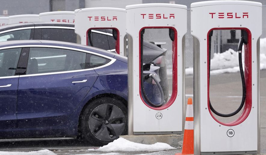 A Tesla electric vehicle sits in a charging station at a dealership in Dedham, Mass., on Thursday, Feb. 18, 2021. (AP Photo/Steven Senne)