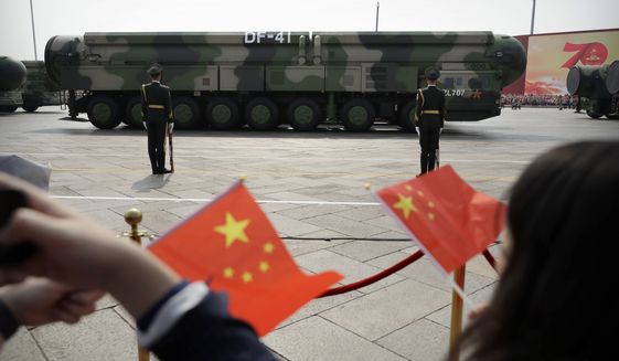 Spectators wave Chinese flags as military vehicles carrying DF-41 ballistic missiles roll during a parade to commemorate the 70th anniversary of the founding of Communist China in Beijing, Oct. 1, 2019. China is expanding its nuclear force much faster than U.S. officials predicted just a year ago, highlighting a broad and accelerating expansion of military muscle designed to enable Beijing to match or surpass U.S. global power by mid-century, according to a Pentagon report released Wednesday, Nov. 3, 2021. (AP Photo/Mark Schiefelbein) **FILE**
