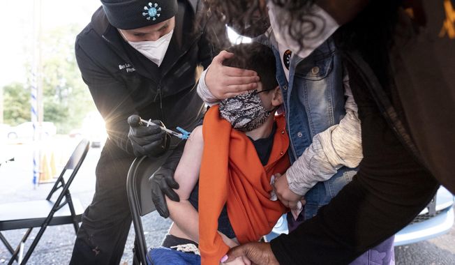 Levi Lefkove, 6, is held by his sister Leah, 9, while getting his first COVID-19 vaccine at the Viral Solutions vaccination and testing site in Decatur, Ga., on the first day COVID-19 vaccinations were available for children from 5 to 12 on Wednesday, Nov. 3, 2021. The U.S. enters a new phase Wednesday in its COVID-19 vaccination campaign, with shots now available to millions of elementary-age children in what health officials hailed as a major breakthrough after more than 18 months of illness, hospitalizations, deaths and disrupted education. (AP Photo/Ben Gray) ** FILE **