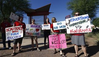 Members of Save Our Schools Arizona protest at the Arizona School for the Arts as Arizona Gov. Doug Ducey tours the school in Phoenix on Aug. 24, 2017. Arizona Gov. Ducey is defying a demand that he stop using federal coronavirus relief money to fund an education grant program that can only go to schools without mask mandates. The Republican governor also is continuing a program that gives private school vouchers to parents upset that their children&#39;s schools require masks or quarantines after being exposed to COVID-19. (AP Photo/Ross D. Franklin) **FILE**