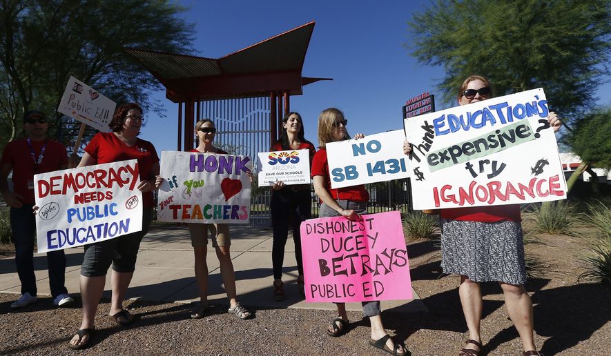 Members of Save Our Schools Arizona protest at the Arizona School for the Arts as Arizona Gov. Doug Ducey tours the school in Phoenix on Aug. 24, 2017. Arizona Gov. Ducey is defying a demand that he stop using federal coronavirus relief money to fund an education grant program that can only go to schools without mask mandates. The Republican governor also is continuing a program that gives private school vouchers to parents upset that their children&#x27;s schools require masks or quarantines after being exposed to COVID-19. (AP Photo/Ross D. Franklin) **FILE**