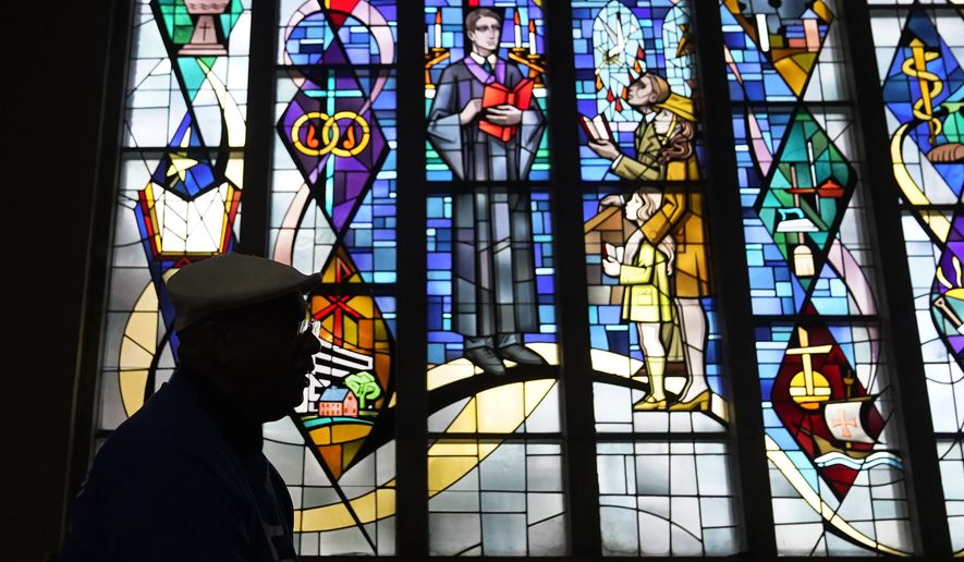 The Rev. Edward Pinkney sits in silhouette at his church as he talks about the lingering water problem for Benton Harbor, Mich., residents Friday, Oct. 22, 2021. (AP Photo/Charles Rex Arbogast)