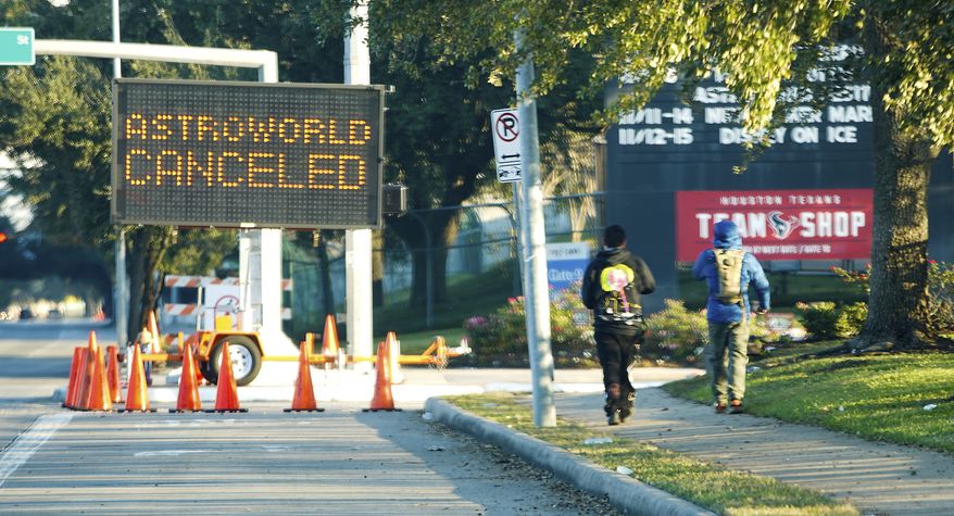 People walk past a sign announcing Astroworld is canceled outside NRG in Houston on Saturday, Nov. 6, 2021.  Several people died and numerous others were injured in what officials described as a surge of the crowd at the music festival while Travis Scott was performing. Officials declared a mass casualty incident just after 9 p.m. Friday during the festival where an estimated 50,000 people were in attendance, Houston Fire Chief Samuel Peña told reporters at a news conference. (Elizabeth Conley/Houston Chronicle via AP)