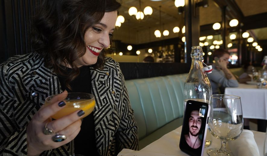 Erin Tridle holds a video chat with her boyfriend Jordan Commarrieu living in Paris from their favorite French restaurant &amp;quot;Petit Trois&amp;quot; in Los Angeles on Friday, Nov. 5, 2021.  Travel restrictions that have separated couples and relatives living in different countries are about to end. New rules go into effect Monday, Nov. 8 that allow air travel from previously restricted countries as long as the traveler has proof of vaccination and a negative COVID-19 test.  (AP Photo/Damian Dovarganes)