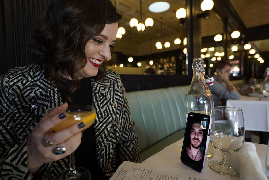 Erin Tridle holds a video chat with her boyfriend Jordan Commarrieu living in Paris from their favorite French restaurant "Petit Trois" in Los Angeles on Friday, Nov. 5, 2021. Travel restrictions that have separated couples and relatives living in different countries are about to end. New rules go into effect Monday, Nov. 8 that allow air travel from previously restricted countries as long as the traveler has proof of vaccination and a negative COVID-19 test. (AP Photo/Damian Dovarganes)